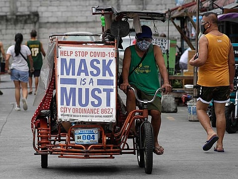 A man rides his pedicab with a slogan to remind people to wear masks to prevent the spread of the coronavirus in Manila.