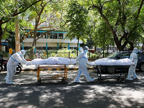 Health workers wearing personal protective equipment carry bodies of people who were suffering from the coronavirus disease outside the Guru Teg Bahadur hospital, in New Delhi, India, April 24, 2021.