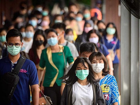 Commuters wearing protective face masks walk on Pratunam pier in Bangkok on April 26, 2021, after the government imposed strict restrictions including a 20,000 THB ($636) fine for not wearing a mask in public following the recent outbreak of COVID-19 coronavirus cases in Thailand.