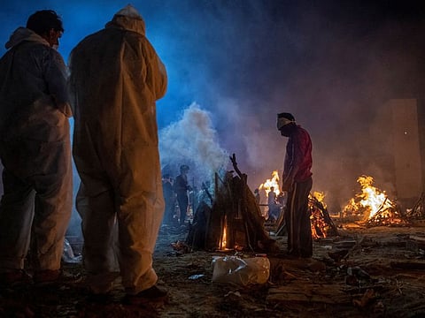 People cremate bodies of victims of coronavirus at a crematorium in New Delhi, India