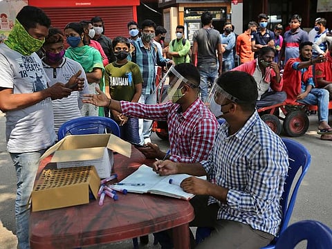 Travellers register themselves with health workers before getting tested for COVID-19 outside a train station in Bengaluru, India, Wednesday, April 28, 2021.
