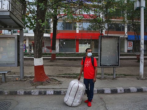 A Nepalese migrant worker who arrived from Saudi Arabia waits for a hitchhike to go back to his village during the first day of lockdown in Kathmandu, Nepal, Thursday, April 29, 2021.