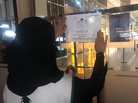 A municipal worker posts a closure notice on a shopping market in Taif.