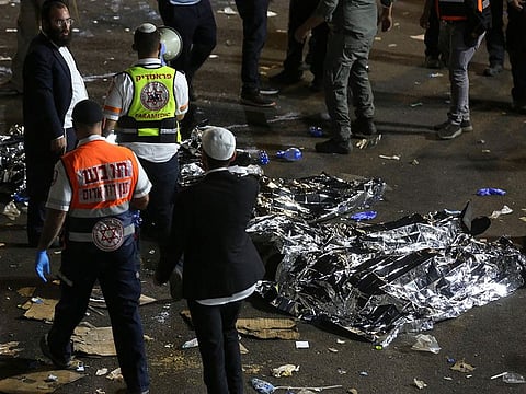 Paramedics stand next to covered bodies after dozens of people were killed and others injured after a grandstand collapsed in Meron, Israel.