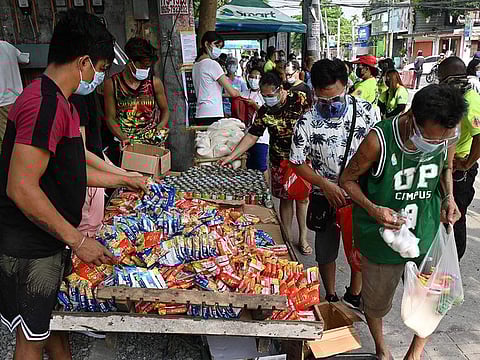 Residents collecting free food packets from a food bank called a "community pantry", run by volunteers, along a road in Quezon City in suburban Manila