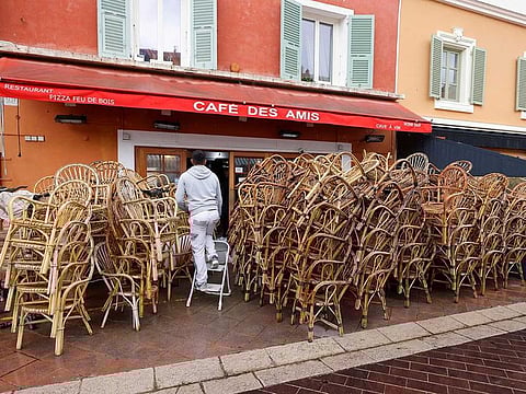 A worker stands on a ladder near chairs stacked on the terrace of a closed restaurant in Nice amid the coronavirus disease (COVID-19) outbreak in France, April 29, 2021.