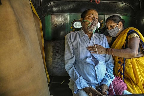 A relative helps a man sitting in the back of a motorized rickshaw receive oxygen for his COVID-19 symptoms, in Delhi, India, April 25, 2021. India’s devastating second wave of coronavirus infections and deaths is tarnishing Prime Minister Narendra Modi’s aura of political invulnerability. (Atul Loke/The New York Times)