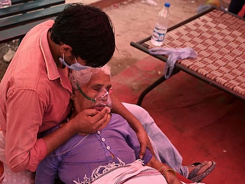 A relative comforts a patient breathing with the help of oxygen provided by a Gurdwara under a tent installed along the roadside amid the COVID-19 pandemic in Ghaziabad, India.