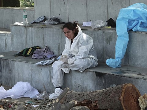 A friend of a person who died of COVID-19 grieves at a crematorium in Jammu, India