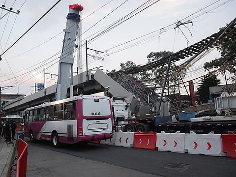 A public bus passes along the street after workers moved two train cars at the accident site, where an overpass of the metro partially collapsed with train cars on it, in Mexico City, Mexico May 4, 2021.