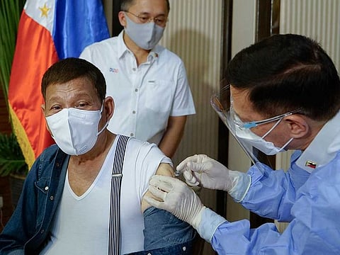 Philippine President Rodrigo Duterte is inoculated with China's Sinopharm COVID-19 vaccine by Health Secretary Fracisco Duque III.