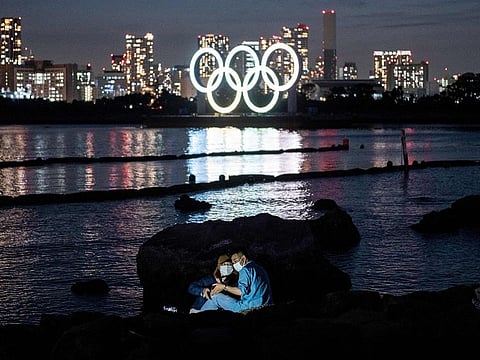 A couple pose for pictures before the lit Olympic rings at the Odaiba waterfront in Tokyo on May 6, 2021.