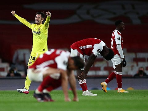 Villarreal's Manu Trigueros celebrates after the match as Arsenal's Bukayo Saka and teammates look dejected.