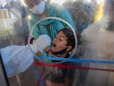 A health worker takes a mouth swab sample of a boy to test for COVID-19 in Srinagar, India