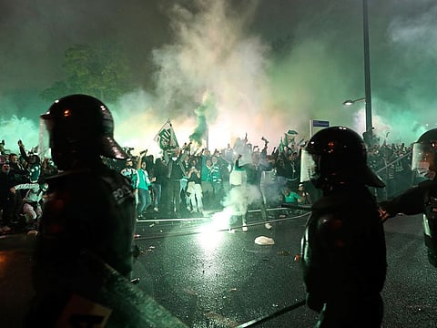 Riot police face off with Sporting fans as supporters bring down fences set along the road