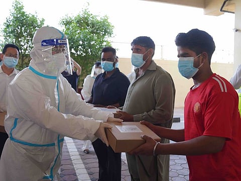 Chinese Consul-General Li Xuhang hands over iftar meal packs at a workers' accommodation in Dubai during Ramadan.