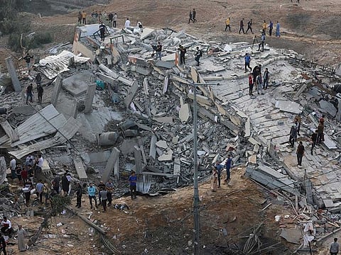 Palestinians gather around a destroyed building on the first day of the Eid Al Fitr holiday, which marks the end of the Muslim fasting month of Ramadan, following Israeli airstrikes on the northern Gaza Strip town of Beit Lahia, early on May 13, 2021.