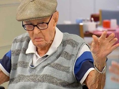 In this image made from video, Australia's Dexter Kruger gestures at a nursing home in the rural Queensland state town of Roma, Australia on May 13, 2021. Kruger, Australia’s oldest-ever man, has included eating chicken brains among his secrets to living more than 111 years.