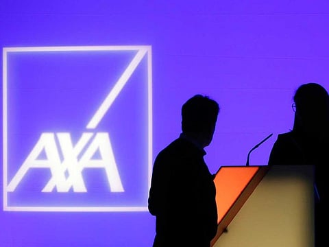In this Feb. 21, 2019, file photo, people stand in front of the logo of AXA Group prior to the company's 2018 annual results presentation, in Paris. The Thai affiliate of Paris-based insurance company AXA said Tuesday, May 18, 2021 it is investigating a ransomware attack by cybercriminals that has affected operations in Thailand, Malaysia, Hong Kong and the Philippines.