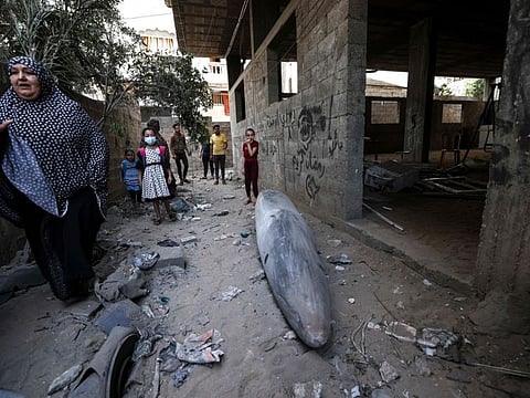 A Palestinian woman stands next to an unexploded bomb dropped by an Israeli F-16 warplane on Gaza City's Rimal neighbourhood on May 18, 2021.