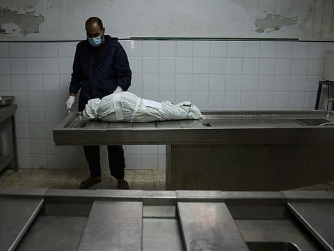 A Palestinian man stands by the body of a three year old girl on May 19, 2021 at a morgue in Gaza City, after she died of her injuries following an Israeli air strike. She is one among 63 children who have been killed by Isreal.