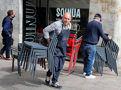 A restaurant worker carries chairs as he prepares the terrace at a restaurant in Bayonne, southwestern France, Tuesday, May 18, 2021. The outdoor terraces of France's cafes and restaurants will be allowed to reopen on May 19 along with museums, cinemas, theaters and concert halls under certain restrictions.