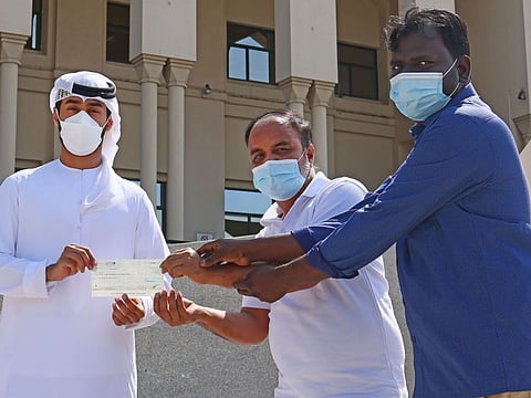 Mohammad Fahad, Administrative- Department of Seasonal Programme of Dar Al Ber Society (left), hands over a cheque of Dhs 200,000 to Shaney Haider (centre) and B. Bharathiraja. The money was collected through donations to help pay the diya (blood money) the two men owe to the family of Utpal Mallik, who accidentally fell to his death while constructing a villa back in 2017.