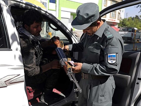 Afghan security personnel checks a gun at a checkpoint around the Green Zone, which houses embassies, in Kabul, Afghanistan, Tuesday, May 25, 2021. Australia is shutting its embassy in the Afghan capital later this week, citing security concerns ahead of the final withdrawal of US and NATO troops.