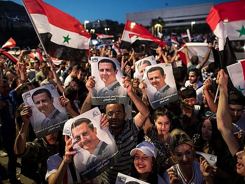 Syrian President Bashar Al Assad supporters hold up national flags and pictures of Assad as they celebrate at Omayyad Square, in Damascus, Syria, Thursday, May 27, 2021.
