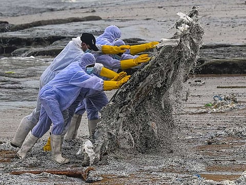 Sri Lankan Navy soldiers work to remove debris washed ashore from the Singapore-registered container ship MV X-Press Pearl, which has been burning for the ninth consecutive day in the sea off Sri Lanka's Colombo Harbour, on a beach in Colombo on May 28, 2021.