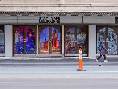 A woman walks past a "Stay Safe Melbourne" sign on a mostly-empty city centre street on the first day of a seven-day lockdown as the state of Victoria looks to curb the spread of a coronavirus disease (COVID-19) outbreak, in Melbourne, Australia, May 28, 2021.