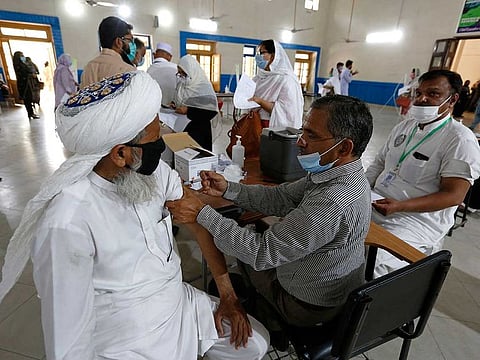 A teacher receives the first shot of the Sinovac coronavirus vaccine from a paramedic in a vaccination centre at a school, in Lahore, Pakistan, Friday, May 28, 2021.