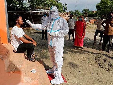 A health worker in protective suit takes a swab sample of a man to test for COVID-19 as others wait for their turn in Kusehta village north of Prayagraj, India, Saturday, May 29, 2021.