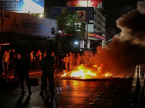 Lebanese soldiers stand guard as smoke rises from tyres set on fire by demonstrators during a protest, after Central Bank said it would stop bank withdrawals from dollar accounts at low fixed rate, in Antelias, Lebanon.