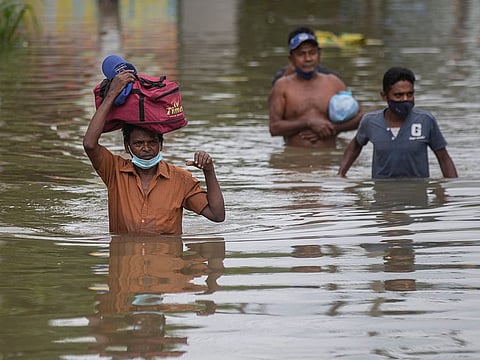 People wade through an inundated street following heavy rainfall at Malwana, on the outskirts of Colombo.