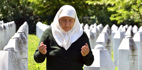 A picture taken on May 26, 2021, shows Bosnian Muslim woman Fadila Efendic, 69, survivor of 1995 Srebrenica massacre, as she prays near tombstones of her husband and son during her visit to the Memorial cemetery in Potocari-Srebrenica set up to honour the victims of the 1995 Srebrenica massacre. Bosnian Serb wartime military chief Ratko Mladic currently awaits the final verdict upon his appeal.