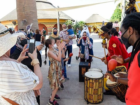 Visitors in masks dance with a band during a parade to mark the last day of the current season at Dubai Safari Park on May 31, 2021.