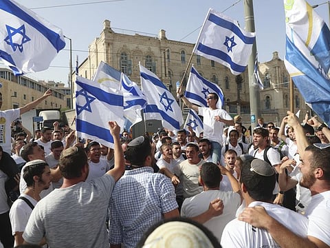 In this May 10, 2021, file photo, Israelis wave national flags during a Jerusalem Day parade. The new government, in which Bennett is to serve as prime minister for two years before handing the job off to Lapid, is expected to come to a vote in the Knesset this week.