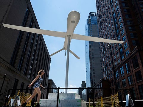A woman walks near a sculpture by artist Sam Durant "Untitled" (drone), a fiberglass sculpture depicting a Predator drone, as it is seen over the High Line park in Manhattan borough of New York.