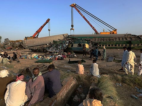Railway workers use crane to remove wreckage to clear the track at the site of a train collision in the Ghotki district, southern Pakistan, Tuesday, June 8, 2021