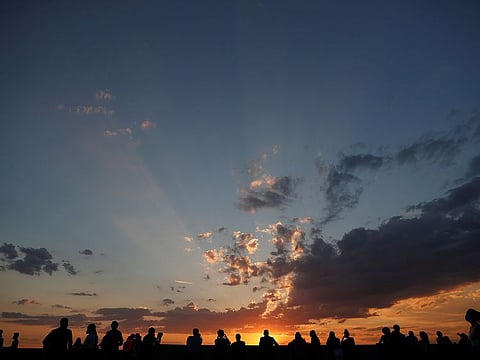People watch the sunset from a lookout by the Royal Palace in Madrid, Spain, June 7, 2021.