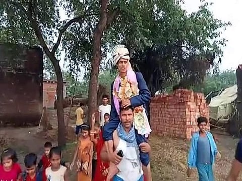 Local TV grabs showed the groom perched on the shoulders of a youth who waded through the muddy pathway and negotiating flooded fields to finally reach the main road.