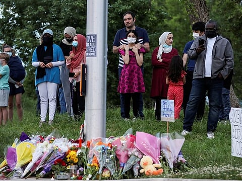 People gather at a makeshift memorial at the fatal crime scene where a man driving a pickup truck jumped the curb and ran over a Muslim family in what police say was a deliberately targeted anti-Islamic hate crime, in London, Ontario.