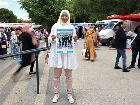 French local election candidate Sara Zemmahi holds her campaign flyer with the slogan 'Different, but united for you' as she poses during an interview for Reuters ahead of the upcoming French local elections in the La Mosson market in Montpellier, France.