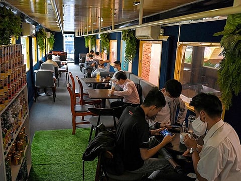 This photo taken on May 31, 2021 shows people sitting in a train carriage that was converted into a cafe at a railway station in Phnom Penh.