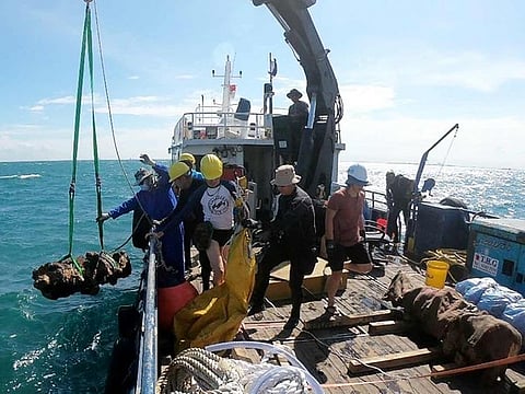 This undated handout photo from the ISEAS - Yusof Ishak Institute shows a cannon, discovered from a shipwreck, being brought onboard a ship in the waters off Pedra Branca, Singapore.