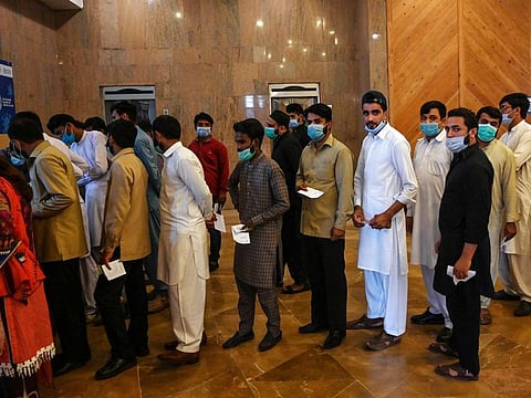 People stand in a queue as they wait to receive a dose of the Covid-19 coronavirus Sinovac vaccine at a mass vaccination centre in Islamabad.
