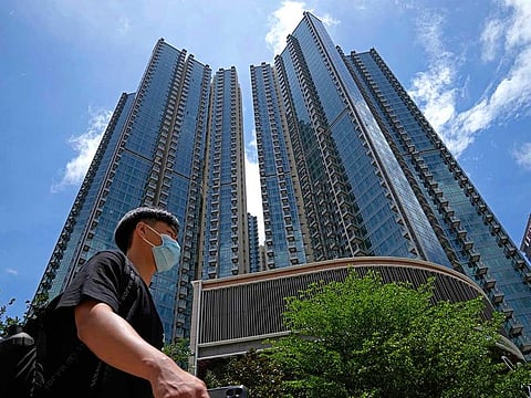 In this Tuesday, June 15, 2021, photo, a man walks in front of the Grand Central residential building complex where one of the HK$10.8 million (US$1.4 million) 449 square feet single-room flats will be offered as a prize in a lucky draw. Coronavirus vaccine incentives offered by Hong Kong companies, including a lucky draw for an apartment, a Tesla car and even gold bars, are helping boost the city’s sluggish inoculation rate.