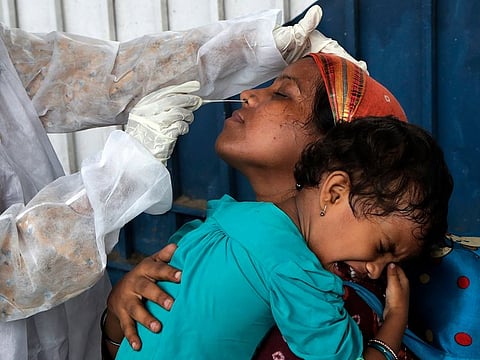 A health worker collects swab sample of traveler to test for COVID-19 at a train station in Mumbai, India, Thursday, June 17, 2021.