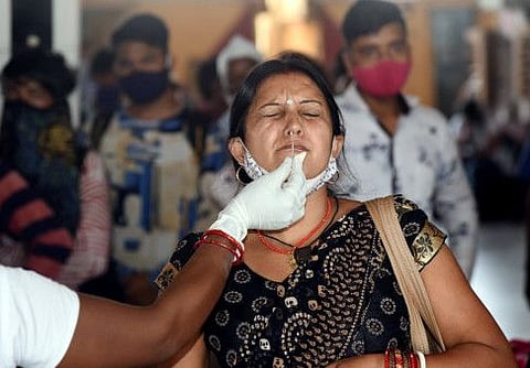 A healthcare worker collects a nasal sample of a passenger at Patna railway station.